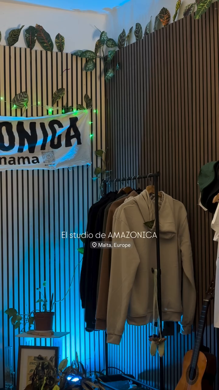 Amazonica studio space with hanging hoodies and green lighting accents